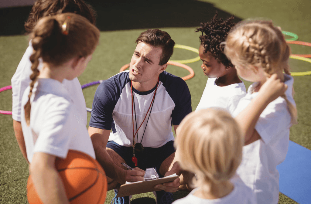Coach instructing children on turf field